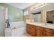 A clean bathroom with white tiled tub, a large mirror, and wooden vanity at 11565 Decatur St # 7D, Denver, CO 80234