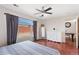 Bright primary bedroom with hardwood floors, dresser, fan, and a large window overlooking the backyard at 15627 E 51St Dr, Denver, CO 80239