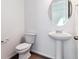 Modern powder room with a pedestal sink, round mirror, and clean, minimalist design, creating a fresh look at 9163 Truckee Ct, Commerce City, CO 80022