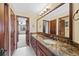 Bathroom featuring double vanity with granite countertop, dark cabinets, and a large mirror at 4 White Fir Ct, Littleton, CO 80127