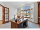 Well-lit home office with a large wooden desk, neutral carpet and a large arched window that floods the room with natural light at 8427 Pierson Ct, Arvada, CO 80005