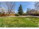 Large, green backyard with mature trees and landscaping, providing ample space for outdoor activities at 5448 S Swadley Ct, Littleton, CO 80127