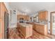 Well-lit kitchen featuring wood cabinets, granite countertops, a kitchen island, stainless steel appliances and hardwood floors at 5448 S Swadley Ct, Littleton, CO 80127