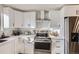 White kitchen cabinets, stainless steel appliances including range and refrigerator, and modern tile backsplash at 8450 Decatur St # 97, Westminster, CO 80031