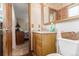 Modest bathroom showing wood vanity, mirror, and view into the connected bedroom at 9400 W Burgundy Ave, Littleton, CO 80123