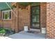 Inviting front porch featuring brick accents, a security screen door, and decorative potted plants at 9400 W Burgundy Ave, Littleton, CO 80123