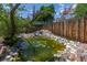 Backyard pond featuring natural rock and water lilies, surrounded by lush greenery and a wooden fence at 9400 W Burgundy Ave, Littleton, CO 80123