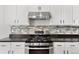 Close up of a kitchen area featuring stainless steel oven, tile backsplash and white cabinets at 2545 Andrew Dr, Superior, CO 80027