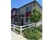 Charming townhome featuring gray siding, a red accent wall, and a welcoming white picket fence at 1353 Reynolds St # 5A, Fort Lupton, CO 80621