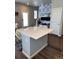 Open living area featuring an island bar with quartz countertop, designer wallpaper, and laminate flooring at 1353 Reynolds St # 5A, Fort Lupton, CO 80621