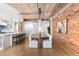 Open-concept dining area with brick wall, wood floors, and a view into the kitchen at 1449 Wynkoop St # 601, Denver, CO 80202