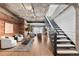 Modern living room with exposed brick, concrete ceiling, and staircase leading to upper level at 1449 Wynkoop St # 601, Denver, CO 80202