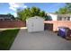 A white shed with brick wall surround in the backyard with a lawn at 2685 W Asbury Ave, Denver, CO 80219