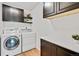Bright laundry room with a modern washer and dryer, sleek countertops, and dark wood cabinets for ample storage at 10016 Teton Ct, Lone Tree, CO 80124