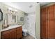 Well-lit bathroom featuring a glass door shower, wood cabinets, and updated fixtures at 1004 Roslyn Ct, Denver, CO 80230