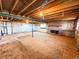 Spacious unfinished basement featuring a brick fireplace, exposed beams, and windows at 1151 Castlewood Pl, Franktown, CO 80116