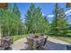 Outdoor patio area with a table, chairs, and fireplace overlooking a wooded landscape at 153 Gold Run Trl, Idaho Springs, CO 80452