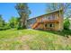 Back exterior view featuring a deck, spacious yard, mature trees, and the home's architectural details at 7448 W Geddes Pl, Littleton, CO 80128