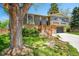 Split-level home featuring a newly built deck and attached two-car garage surrounded by mature trees at 7448 W Geddes Pl, Littleton, CO 80128
