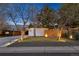 Modern home exterior featuring well-lit landscaping, white walls, and a wood fence creating a warm, inviting curb appeal at 1486 S Elm St, Denver, CO 80222