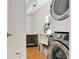 Well-lit laundry room with stacked washer/dryer, storage shelves, and pet crate area at 1486 S Elm St, Denver, CO 80222