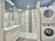Modern bathroom with tiled shower, sliding glass doors, modern vanity, and stacked washer and dryer at 1834 Hennington Ct, Longmont, CO 80501