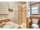Tiled bathroom features a glass-enclosed shower, wainscotting, wood trim window, and a round bowl sink at 1834 Hennington Ct, Longmont, CO 80501