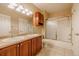 Bathroom featuring a double sink vanity with wood cabinets and a tub with glass doors at 10085 Charissglen Ct, Highlands Ranch, CO 80126