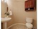 Traditional half bathroom featuring pedestal sink and toilet, and a wall cabinet providing extra storage at 10085 Charissglen Ct, Highlands Ranch, CO 80126