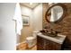 Stylish powder room with a unique vessel sink, stone accent wall, and elegant mirror, adding a touch of sophistication at 10085 Charissglen Ct, Highlands Ranch, CO 80126