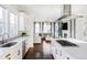 Bright kitchen boasts white cabinets, an island with cooktop, and open concept living space at 6003 Chester Way, Denver, CO 80238