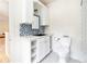 Charming bathroom with blue tile backsplash, white cabinets and shelving, hexagon tile flooring, and modern fixtures at 1512 Cottonwood Ln, Greenwood Village, CO 80121