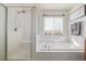 Bright bathroom featuring double sinks, wood cabinetry, a bathtub, and a separate glass enclosed shower at 12133 Hannibal St, Commerce City, CO 80603
