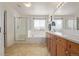 Bright bathroom featuring double sinks, wood cabinetry, a bathtub, and a separate glass enclosed shower at 12133 Hannibal St, Commerce City, CO 80603