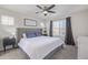 A light filled main bedroom with a large upholstered headboard, ceiling fan and large picture window at 12133 Hannibal St, Commerce City, CO 80603