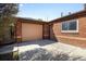 Garage and brick exterior with a light tan door and a concrete driveway on a sunny day at 1560 Pueblo Ct, Thornton, CO 80229