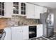 This kitchen features white cabinetry, stainless steel appliances, and modern backsplash at 1560 Pueblo Ct, Thornton, CO 80229