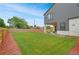 Large backyard featuring green lawn space, modern gray siding, stone accents, covered patio, and a wooden fence at 3343 S Newcombe St, Lakewood, CO 80227