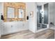 Luxurious bathroom featuring a double vanity, wood accent wall, glass-enclosed shower, and modern design at 3343 S Newcombe St, Lakewood, CO 80227