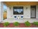 Charming front porch with a stone facade, black trimmed windows, outdoor seating, and landscaped greenery at 3343 S Newcombe St, Lakewood, CO 80227