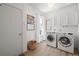 Bright laundry room featuring a front-load washer and dryer set, storage cabinets, and wood-look tile flooring at 10385 E Ida Ave, Greenwood Village, CO 80111