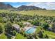 Aerial view of community pool, tennis court, lush landscaping, and mountain backdrop at 19 Benthaven Pl, Boulder, CO 80305