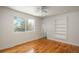 Sunlit bedroom featuring built-in shelves, hardwood floors, and a ceiling fan for added comfort at 8170 S Marshall Ct, Littleton, CO 80128
