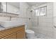 Modern bathroom featuring sleek wood vanity, granite countertop, and frameless glass shower with tile surround at 8333 Depew Way, Arvada, CO 80003