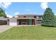 Charming brick home with well-manicured lawn, a blue door, and attached garage at 8333 Depew Way, Arvada, CO 80003