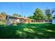 An expansive backyard featuring lush green grass, a covered patio, storage shed, and partial privacy fence at 2814 S Winona Ct, Denver, CO 80236