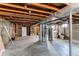 Unfinished basement with a laundry area, toilet, shelving and exposed wood ceiling at 1170 Kingston St, Aurora, CO 80010