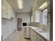 A white galley kitchen featuring tiled countertops and open shelving at 4514 Bryant St, Denver, CO 80211