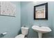 Charming half bath features a pedestal sink and blue walls with decor at 139 N Prairie Falcon Pkwy, Brighton, CO 80601