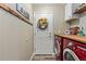 Well-organized laundry room with modern red washer and dryer, and decorative wreath on door at 139 N Prairie Falcon Pkwy, Brighton, CO 80601